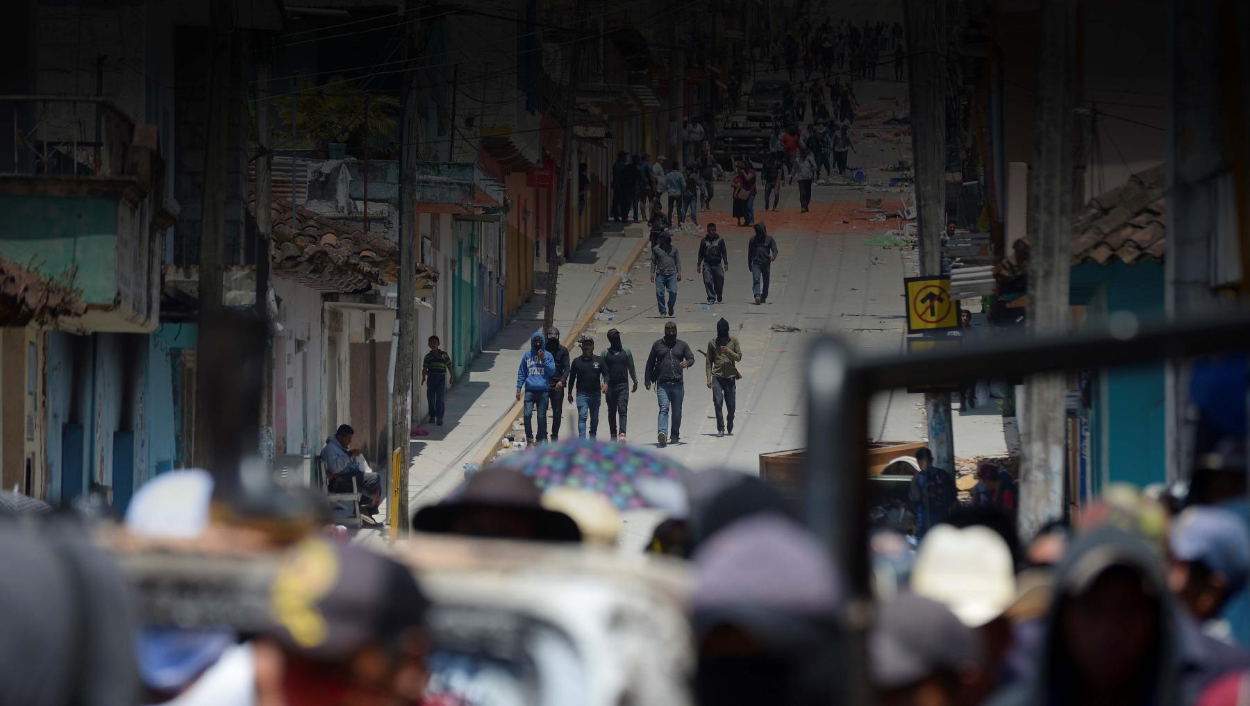 Residents and members of the new self-defense group known as 'El Machete' stand next to a burnt truck as others look for members of drug gangs and municipal authorities during a protest against the growing violence in the area, in Pantelho, in Chiapas state, Mexico 27 July, 2021.