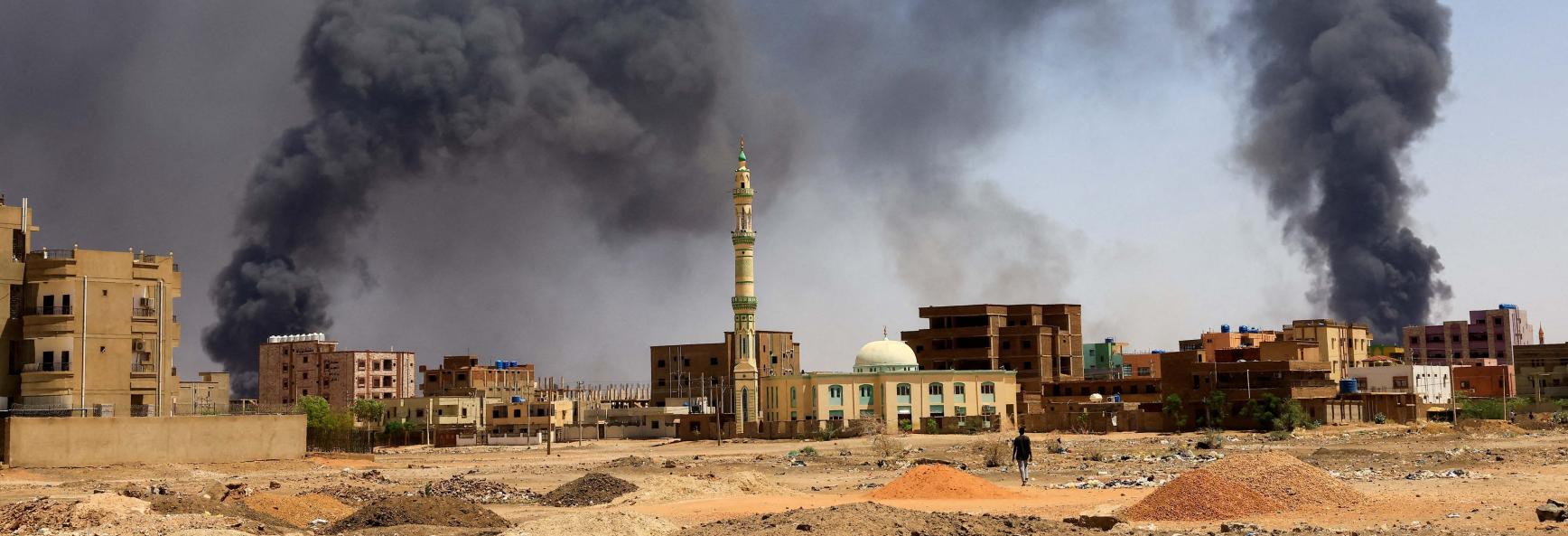 A man walks while smoke rises above buildings after aerial bombardment, during clashes between the paramilitary Rapid Support Forces and the army in Khartoum North, Sudan, May 1, 2023. 