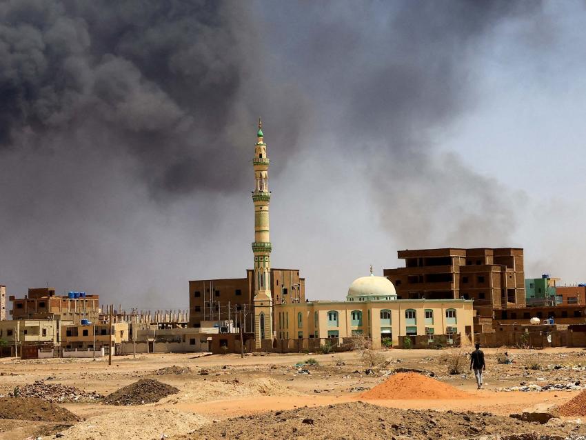 A man walks while smoke rises above buildings after aerial bombardment, during clashes between the paramilitary Rapid Support Forces and the army in Khartoum North, Sudan, May 1, 2023. 