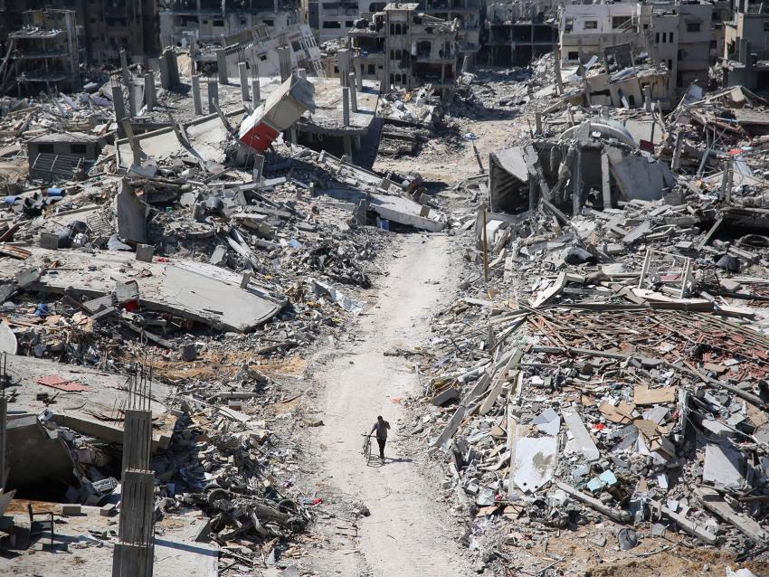 Editorial photo of destruction and a man walking with a bicycle in Gaza